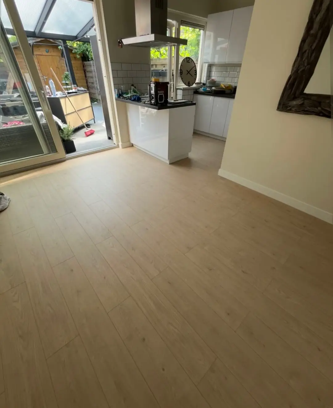 Nieuwe vloer in houtlook doorgelegd tot in de open keuken met schuifpui naar de tuin